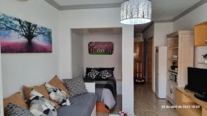uma sala de estar com um sofá e uma árvore na parede em Estudio céntrico en Torremolinos em Torremolinos