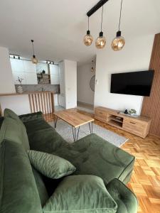 een woonkamer met een groene bank en een flatscreen-tv bij ZARA Apartman Živinice in Živinice