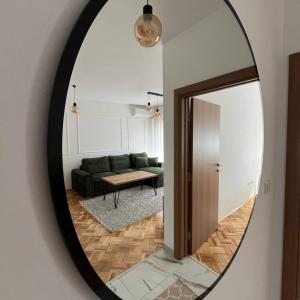 een spiegel met een woonkamer met een groene bank bij ZARA Apartman Živinice in Živinice