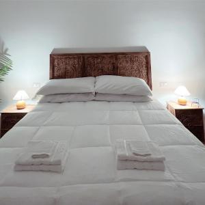 een groot bed met witte lakens en 2 nachtkastjes bij Maison Frida • Tivoli in Tivoli
