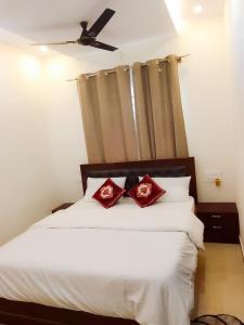 Private Paradise Opposite Nandi Hills في بانغالور: غرفة نوم بسرير ابيض ومخدات حمراء