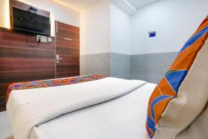 a bedroom with a bed with a tv on the wall at FabExpress Ashoka Inn - Nr Mumbai International Airport in Mumbai