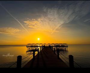 un muelle con la puesta de sol sobre el agua en 5-BR beachfront Villa on Red Sea - stunning view, en Ain Sokhna