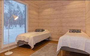 two beds in a room with a window at Villa Paadari in Inari