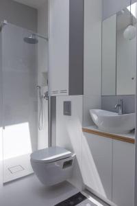 a white bathroom with a toilet and a sink at Sunny Mokotow - apartment near the metro in Warsaw