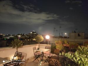 a table and chairs on a balcony at night at Hotel Byron in Athens