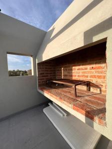 Casa terraza Quequén في قويقوين: غرفة بها موقد من الطوب ومقعد