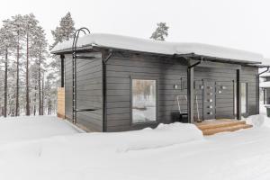 une petite cabine dans la neige dans les bois dans l'établissement Villa Paadari, à Inari