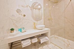 uma casa de banho branca com um lavatório e um chuveiro em Hotel Artemis em Oradea