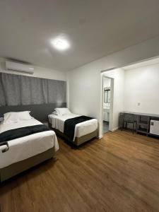 a hotel room with two beds and a mirror at Hotel do Vale in Campina Grande