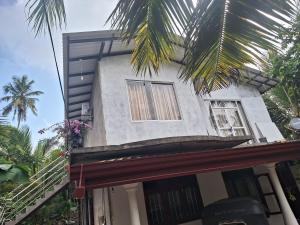 een huis met een palmboom ervoor bij Alali Villa in Bentota
