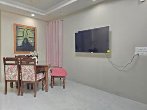 een woonkamer met een tafel en een tv aan de muur bij Homlee-Saket Anupam Stylish 3BHK in South Delhi in New Delhi