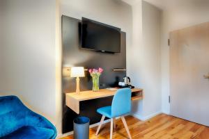 Dieses Zimmer verfügt über einen Schreibtisch mit einem blauen Stuhl und einen TV. in der Unterkunft martas Hotel Berlin-Mitte in Berlin