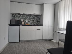 a white kitchen with white cabinets and a window at Julien Central Home in Galaţi +6 photos