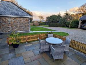 a patio with a table and chairs in a backyard at Mariners Rest in Gorran Haven