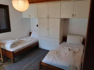 two beds in a room with white cabinets at Fani Apartment in Skotiní