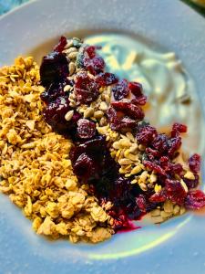 a plate of granola with berries and cream on it at Bransford Farm Fishery & B & B in Bransford