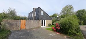 a house with a black roof and a brick wall at Beautifull house Beach Life 47 in De Cocksdorp