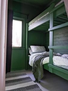 a green room with two bunk beds and a window at Kesäelo in Porvoo