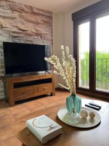 sala de estar con TV y jarrón con flores en Acogedor y Céntrico Apartamento en Mora de Rubielos