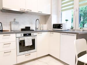 a white kitchen with a stove and a microwave at Fancy Life Apartment in Warsaw