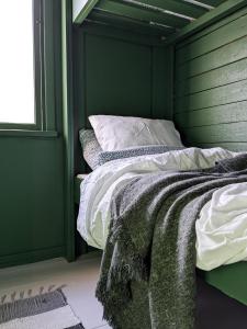 a green room with a bed with white sheets at Kesäelo in Porvoo
