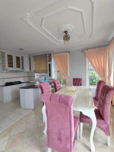 ein Esszimmer mit einem weißen Tisch und rosa Stühlen in der Unterkunft Vila Princess,Sentul 4br, private pool, tenis meja, mini billiard, Home theater Karaoke, Ayunan besar,BBQ, 08satu3 80satu6 4satu5satu in Bogor