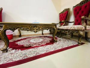 Habitación con 2 sillas y alfombra roja. en Serene Nest, en Umm Al Quwain