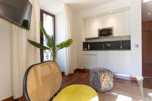 sala de estar con silla amarilla y cocina en La Casa de la Alameda, en Málaga