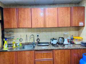 a kitchen counter with wooden cabinets and a sink at Serene Nest in Umm Al Quwain