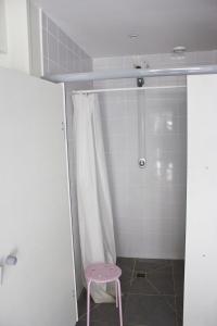 baño con ducha y taburete rosa en Fontaineblhostel hostel & camping near Fontainebleau, en La Chapelle-la-Reine