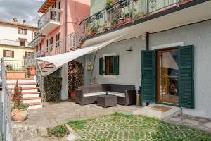 eine Terrasse mit einem Sofa und einem Tisch neben einem Gebäude in der Unterkunft Casa Galya with private patio by GardaDoma in Brenzone sul Garda