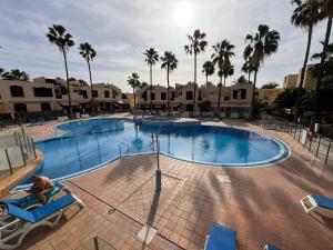a large swimming pool with palm trees in a resort at Alquilaencanarias Tagoro Paradise in Costa Del Silencio +4 photos