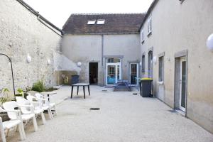 um pátio com cadeiras e uma mesa num edifício em Fontaineblhostel hostel & camping near Fontainebleau em La Chapelle-la-Reine