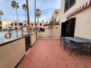 a patio with a table and chairs next to a building at Alquilaencanarias Tagoro Paradise in Costa Del Silencio