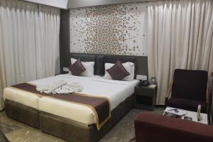 a bedroom with a large bed and a chair at Continental Lodge & Continental Residency in Māldah