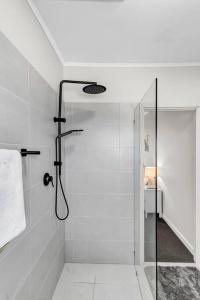 a white bathroom with a shower with a glass door at TheWest36 - Sandy Escape in Henley Beach South