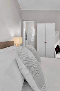 a white bed with white sheets and pillows at TheWest36 - Sandy Escape in Henley Beach South