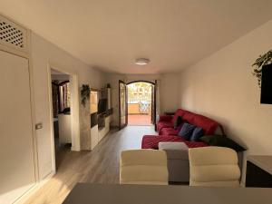 a living room with a red couch and white chairs at Alquilaencanarias Tagoro Paradise in Costa Del Silencio