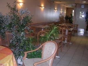 un restaurant avec des tables en bois, des chaises et des plantes dans l'établissement Hotel Asteries, à Tours