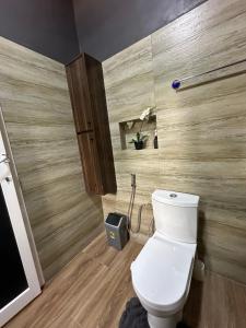 a bathroom with a toilet and a wooden wall at The loft/lilysvilla in Agbédinou