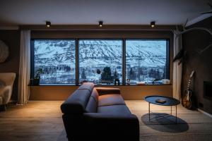 een woonkamer met een bank voor een groot raam bij Botnahlid Villa in Seyðisfjörður
