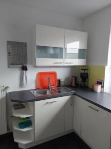 eine Küche mit weißen Schränken, einer Spüle und einem orangen Stuhl in der Unterkunft Ferienwohnung Hiddesen in Detmold