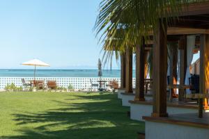 a beach with tables and chairs and an umbrella at Pousada Mansão da Costa in Maragogi