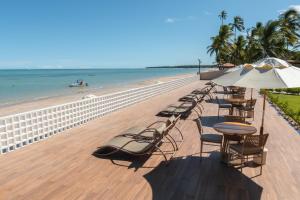 Pousada Mansão da Costa في ماراغوغي: صف من الكراسي والطاولات ومظلة على الشاطئ
