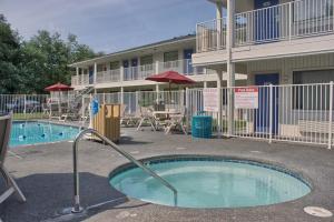 uma piscina em frente a um edifício com mesas e cadeiras em Motel 6-Seattle, WA - South em SeaTac