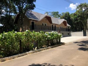 a house with white flowers in front of a street at La Floresta Suites in Campos do Jordão
