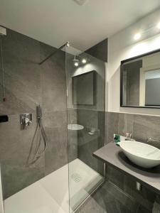 W łazience znajduje się szklana kabina prysznicowa i umywalka. w obiekcie Alla Casa Di Giò w Mediolanie