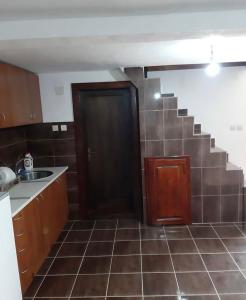 a kitchen with a black door and a tile floor at Veskov Konak in Andrijevica