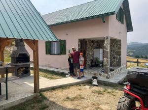un hombre y dos niños parados frente a una casa en Veskov Konak, en Andrijevica